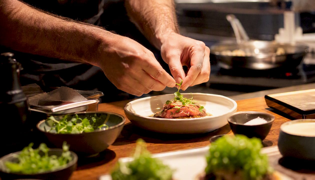 Chef preparing tasting menu course at Kitchen Table counter