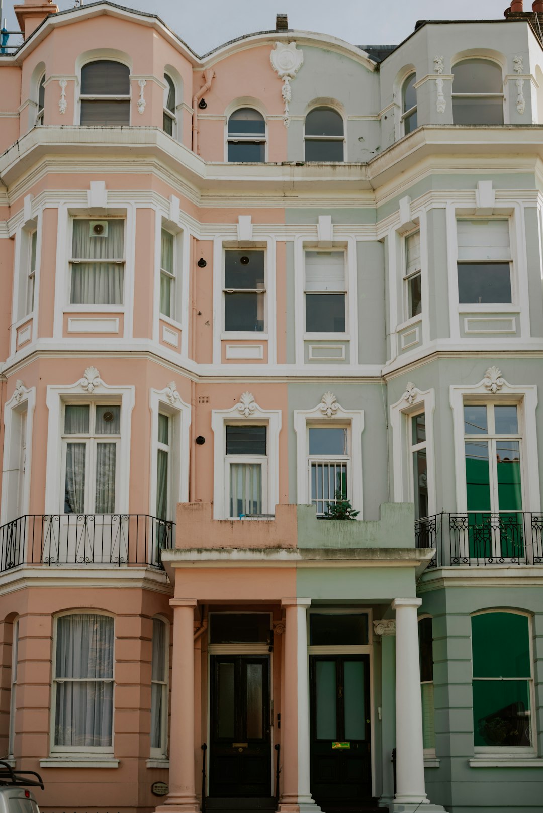 Pastel-coloured terraced houses on a Notting Hill street with flower-adorned balconies, West London